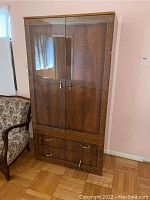 Front view of the wooden armoire showing two glass doors and two bottom drawers.