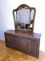 Front view of the wood dresser with mirror on top showing drawer arrangement, handles, and ornate mirror frame.