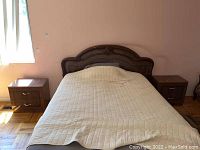 Full view of a bed with matching wooden nightstands on each side, showing the relative size and placement of the nightstands.