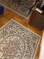 Smaller floral patterned area rug with frayed corners on wooden floor near furniture