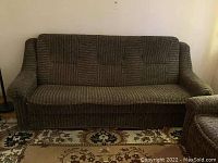 Front view of the black and tan textured upholstered sofa, showing the full seating area and arms.