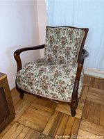 Front view of vintage wooden armchair with floral upholstery showing wood frame, curved armrests, and cushioned seat and back.