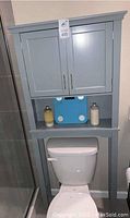 Over-the-toilet storage cabinet with two doors, placed above toilet. Shows the cabinet size and color.