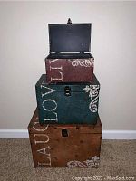 Stacked set of three decorative metal boxes showing 'LAUGH', 'LOVE', 'LIVE' text from front.