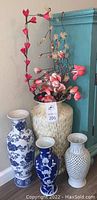 Overview of large white ceramic floor vase with shell inlay and artificial flowers, alongside three smaller decorative vases in blue and white.