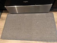 Gray cushioned kitchen mat with herringbone pattern under oven/stove.