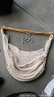Beige hanging macrame chair laid out with metal hanging hardware pieces on the floor.