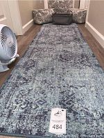 Aqua and navy blue runner rug laid on floor, with floral laundry baskets and black laundry basket at the end