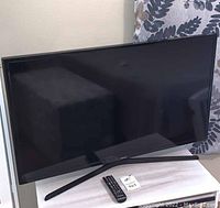 Black 40-inch Samsung Smart TV resting on a light-colored cabinet with a black remote on the surface.