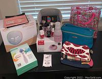 Overview of all items on table, boxed beauty mask, blackhead remover, nail lamp, nail polish, makeup bags