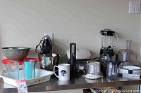 Full view of kitchen countertop with various appliances and bowls including Sunbeam mixer, Cuisinart blender, Pyrex bowls, and more