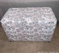 Closed floral storage ottoman showing fabric pattern and shape.
