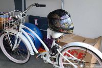 Full side view of white Jones Dream Ride bicycle with pink rims and black Scorpion EXO-T150 motorcycle helmet on the seat.
