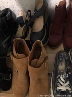 Photo of various women's shoes including boots, wedge heels, flats, and sneakers arranged inside a box.
