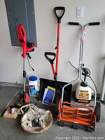 Photo showing full lot including American brand push mower, SnoJoe snow shovel, Powersmart weed whacker with accessories, garden hose, Ice Melt container, and clay birdbath