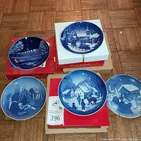 Five Bing & Grondahl blue and white collector plates displayed on floor showing various winter and Christmas scenes, each on original boxes