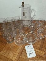 Full set overview showing 10 tumblers, 5 champagne glasses, pitcher, sugar bowl, and creamer on wooden floor