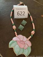 Full view of necklace and earrings on dark background with auction lot number visible