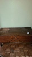 Top view of rectangular wooden chest with worn surface and scratches.