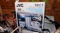 Photo of boxed JVC TH-C3 DVD Digital Theater System showing front and side of the box with product image and multilingual text.