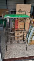 Full view of the metal frame wine rack with the green glass top and bottle storage slots