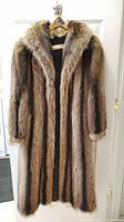 Front full view of the long raccoon fur coat hanging on branded WM. H. Harris hanger.