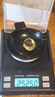 Photo of oval cut golden citrine gemstone on a digital scale showing weight 25.25 carats.