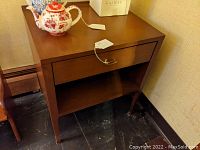 Front and side view of the brown mid-century nightstand with a drawer and open shelf showing overall good condition.