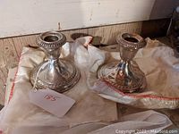 Photo of two Gorham sterling silver weighted candlesticks resting on white cloths showing their overall design and condition.