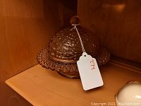 Side view of the covered pink hobnail glass dish with a dome lid and finial handle