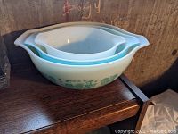 Three nesting Pyrex Cinderella mixing bowls with blue Amish Butterprint design showing handles and nested interior bowl sizes.