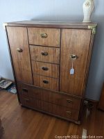 Full front view of tall chest showing six drawers, side cupboard doors and brass hardware