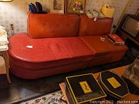 Full view of red vinyl sofa with curved right end, three button-tufted back cushions and three seat cushions