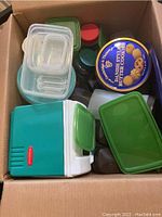 View of box showing Rubbermaid cooler, assorted plastic containers and lids, Danish butter cookie tin and plastic platter