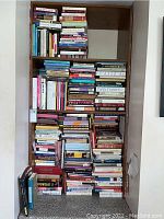 Bookshelves filled with numerous books arranged horizontally and vertically, showing a large diverse collection.