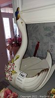 Front view of white porcelain swan planter with applied pink and yellow floral decorations and golden beak and eyes.