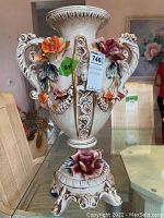 Full view of the Capodimonte ceramic centerpiece vase, showing floral accents, ornamental handles, and pedestal base