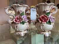 Front view of both ornate Capodimonte-style ceramic vases with prominent pink and lavender porcelain flowers attached.