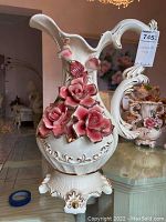 Front view of Capodimonte porcelain vase showing pink rose floral decorations, ornate handle, and gold accents on footed base.