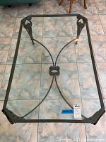 Full view of glass coffee table showing rectangular shaped top with beveled edges and decorative metal frame with scroll details