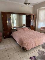 Left wall unit positioned behind a bed, visible mirrored panel and wood finish with brass accents.