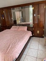 Right wall unit installed behind a bed, showing wood doors and mirrored center section.