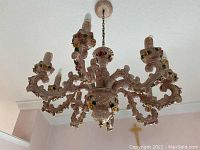 Full view of the porcelain chandelier hanging from ceiling showing its six arms and floral decor.