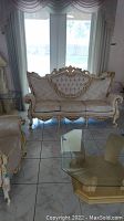 Full frontal photo of the French Provincial style sofa showing the tufted backrest, three seat cushions, and carved wood frame with gold accents.