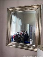 Front angled view of a rectangular wall mirror with a gold frame showing wear and reflective glass.