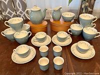 Full set displayed on table showing 24 pieces including cups, saucers, teapot, milk jug, and bowl.