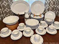Photo showing complete service for nine place settings including teacups, saucers, dinner plates, salad plates, and coupe soup bowls arranged on a table along with larger serving pieces.