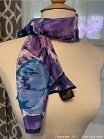 Scarf tied around mannequin neck showing blue and purple floral pattern and smooth texture.