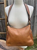 Front view of vintage La Diva tan leather handbag on mannequin showing overall shape, color, and strap attachment with metal rings.