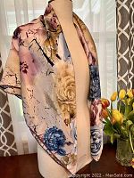 Scarf draped over dress form showing floral pattern and silky texture.